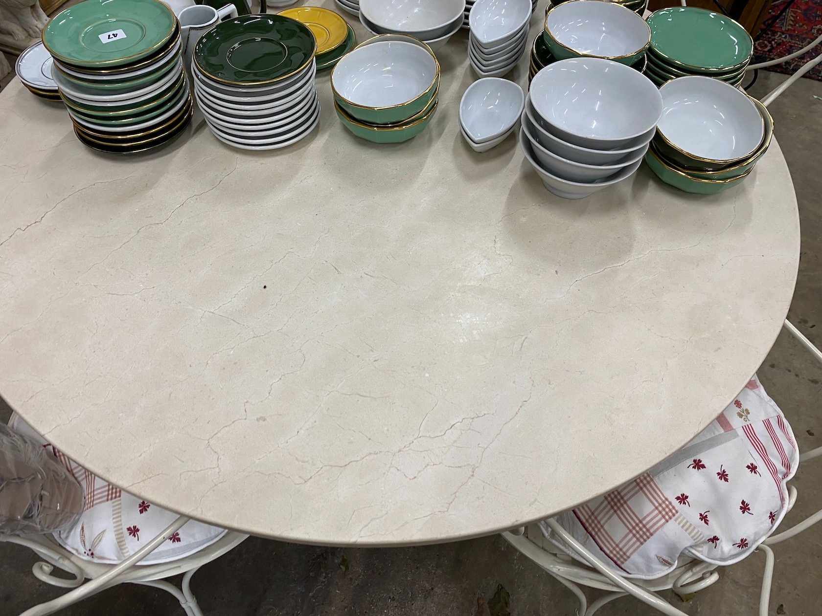 A circular reconstituted marble garden table, diameter 120cm, height 74cm and four painted wrought iron chairs